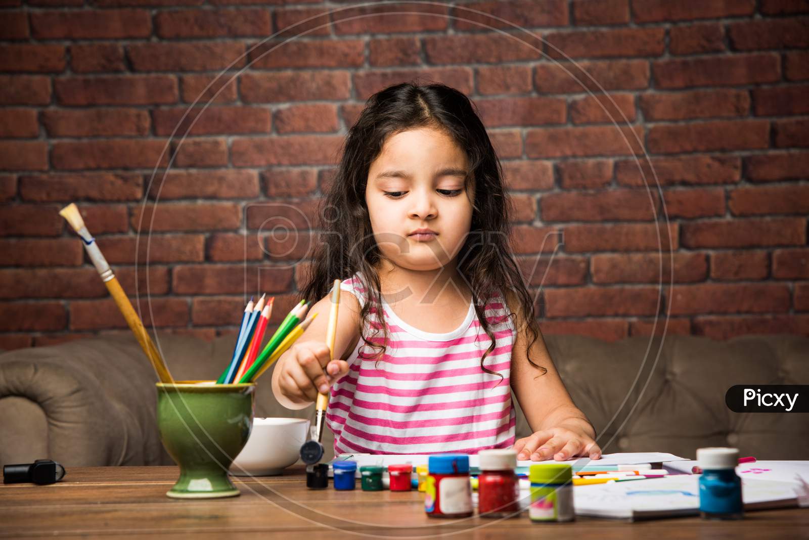Indian small girl drawing / Painting with colours over paper, selective focus