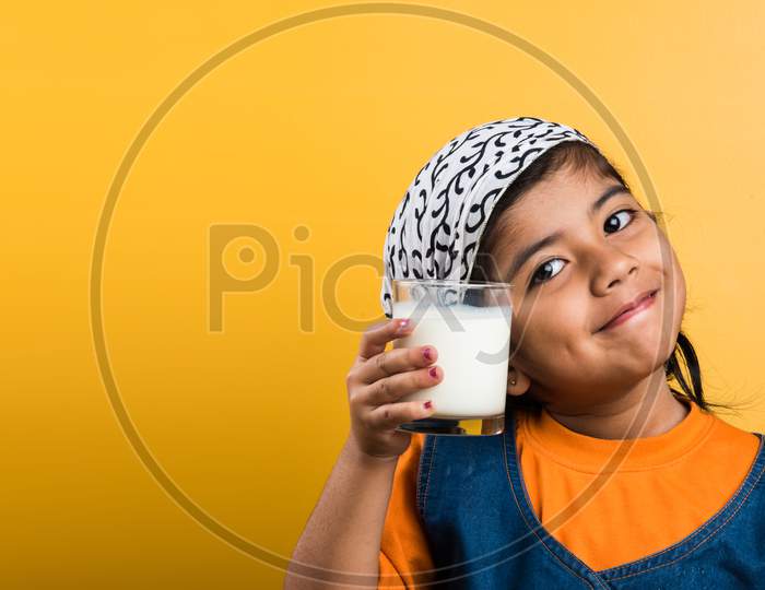 Small girl drinking plain milk in a glass before going to school