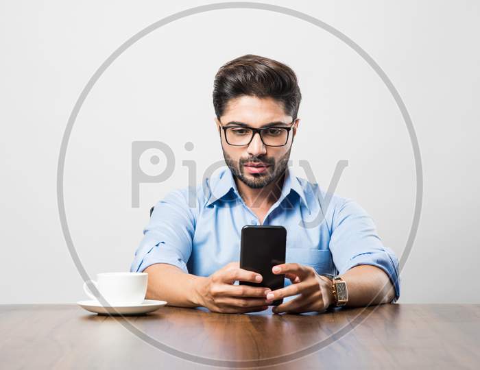 Indian business man using cell phone. Having Conversation or typing or checking social media feeds