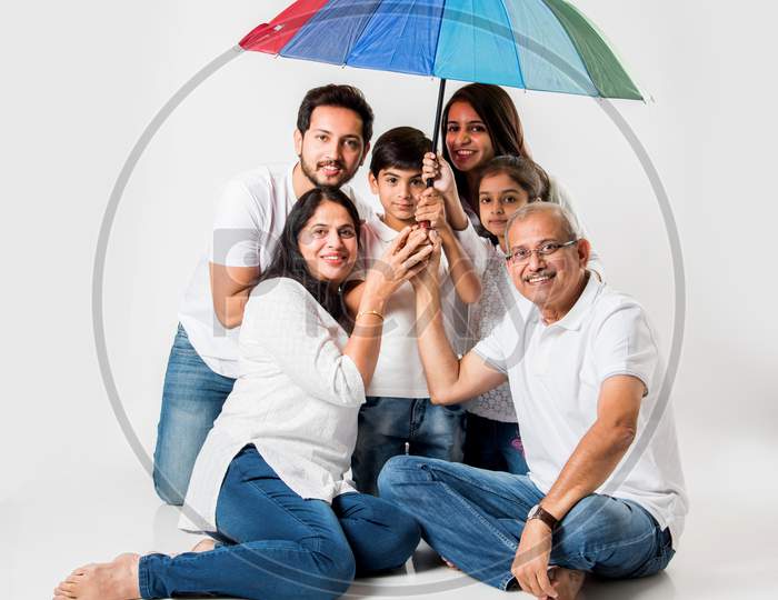Indian Family sitting with Umbrella over white background. selective focus