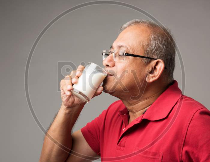 Senior Indian / asian man with a glass of milk and or fresh apple - healthy old age concept