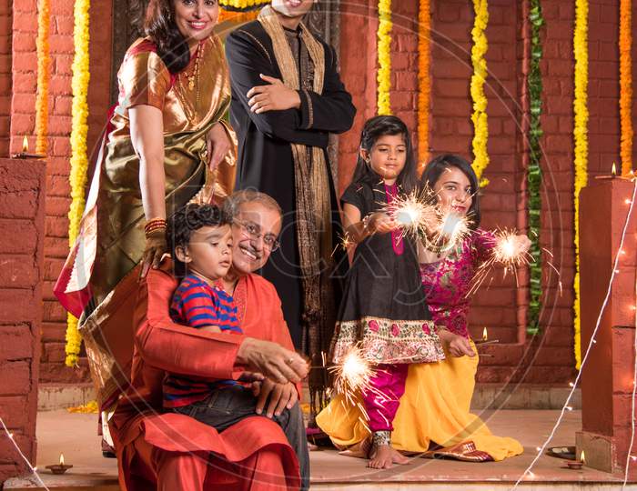 Indian Family celebrating Diwali festival with fire crackers