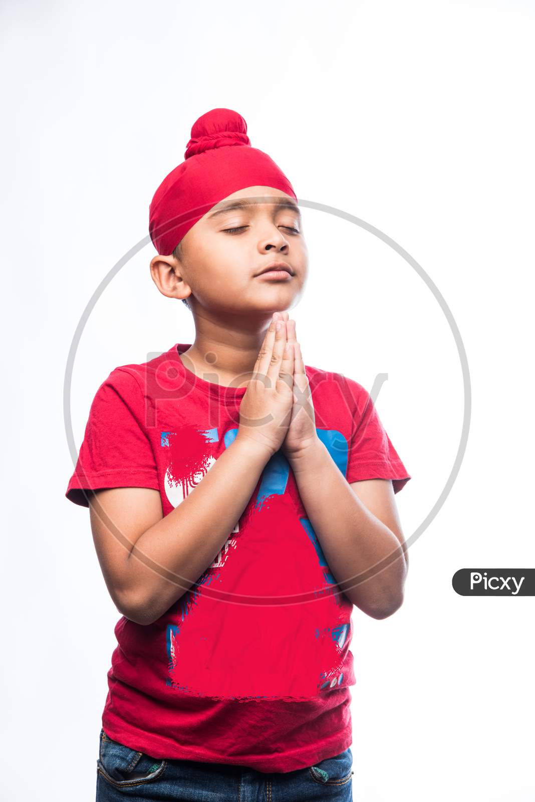 Portrait of Indian Sikh/punjabi little boy praying while standing isolated over white background