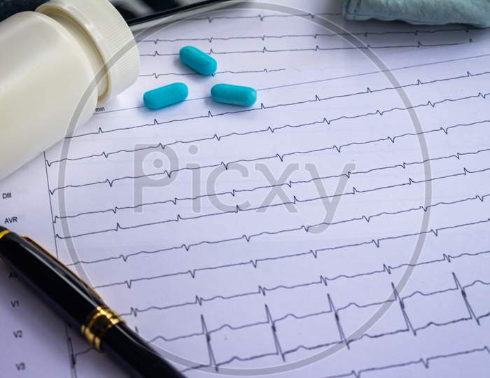 Top View Of A Desk With Various Elements Of Medicine. Pills On Electrocardiogram