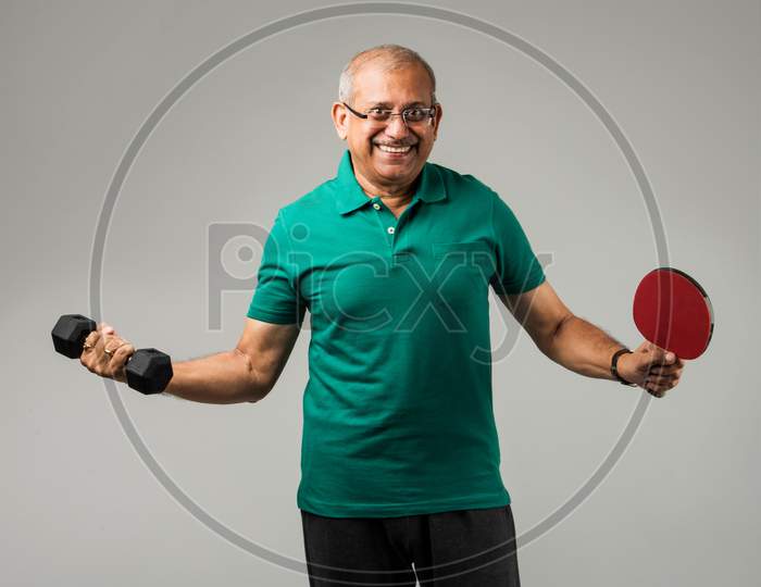 Senior indian man doing weight training / gym