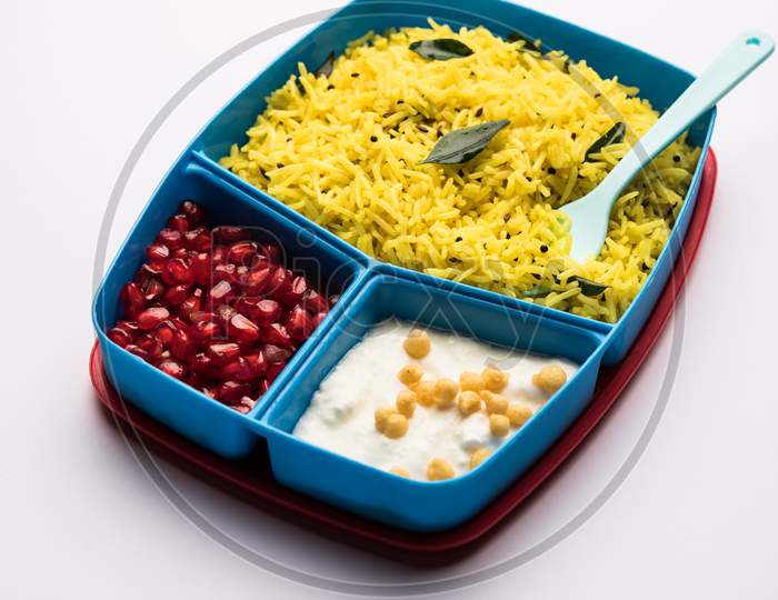 Lunch Box / Tiffin for Indian kids, contains lemon rice, nahi-boondi and pomegranate or Anar. selective focus
