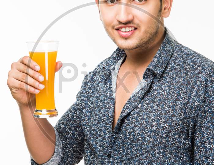 Young man having cold drink or fresh juice in a glass
