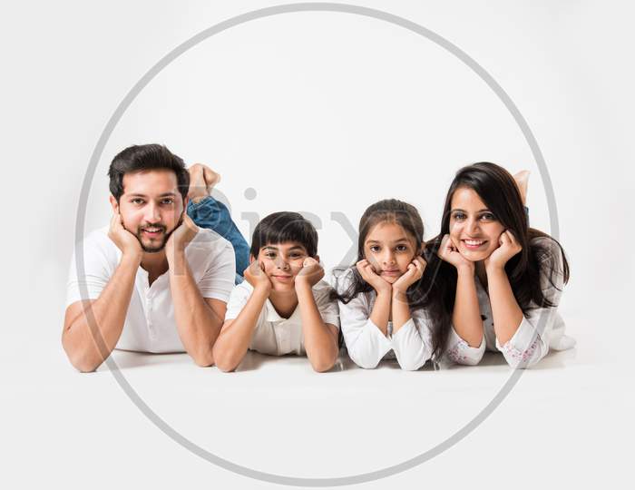 Young family lying on white looking at camera