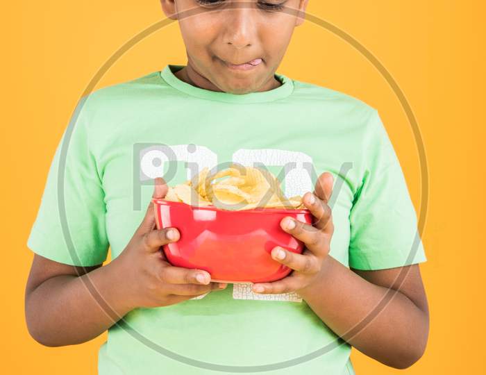 Cute little boy eating potato wafers or crispy chips
