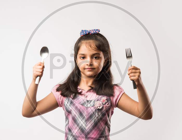 Small Girl showing spoon and fork over white background
