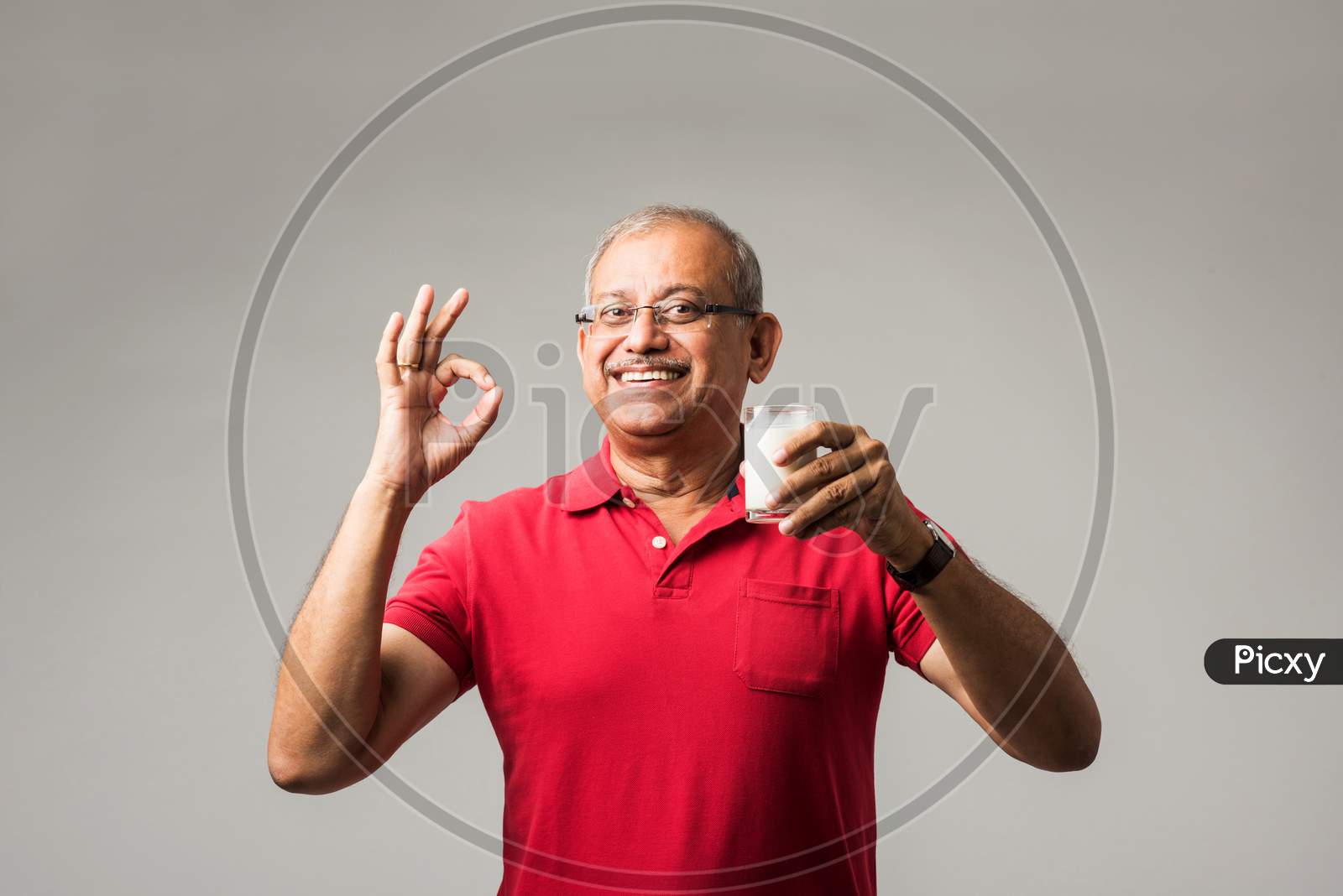 Senior Indian / asian man with a glass of milk and or fresh apple - healthy old age concept