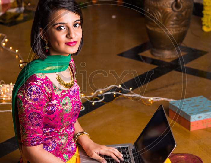 Young girl online shopping using laptop computer on festival night
