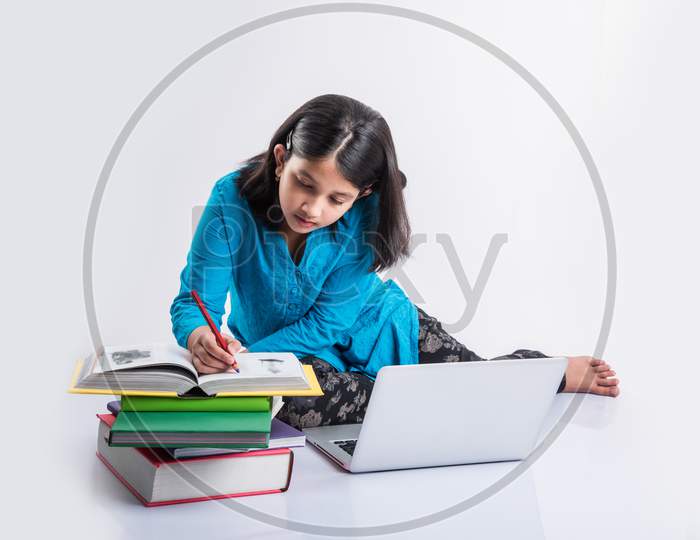 Indian school girl studying with laptop and books
