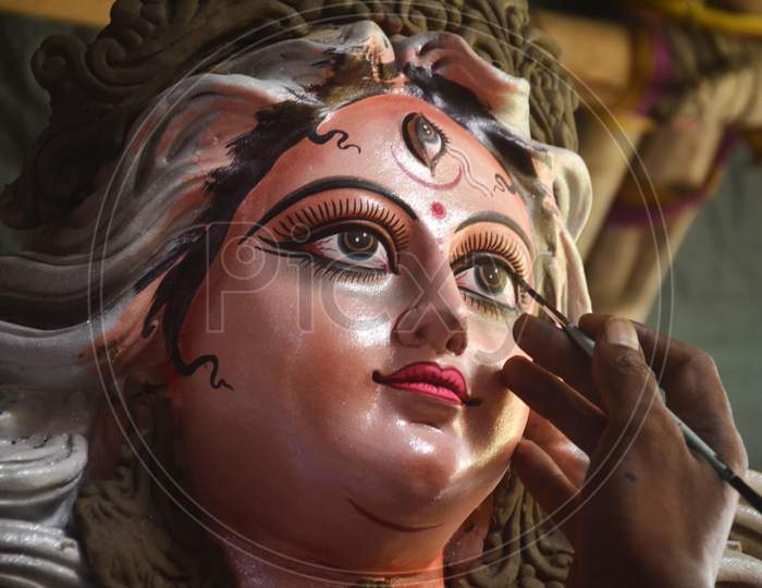 An artist gives final touches to an idol of Goddess Durga