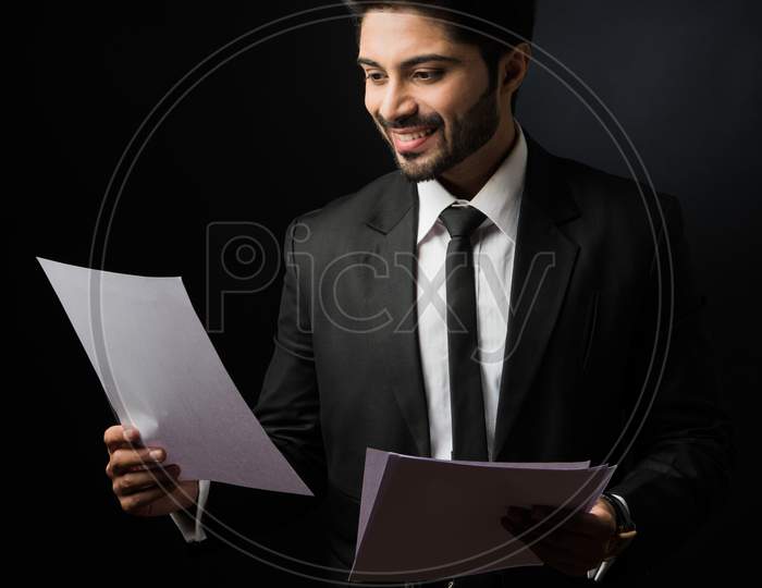 Indian Bearded Male businessman holding or reading documents or paper Roll while standing isolated over white background