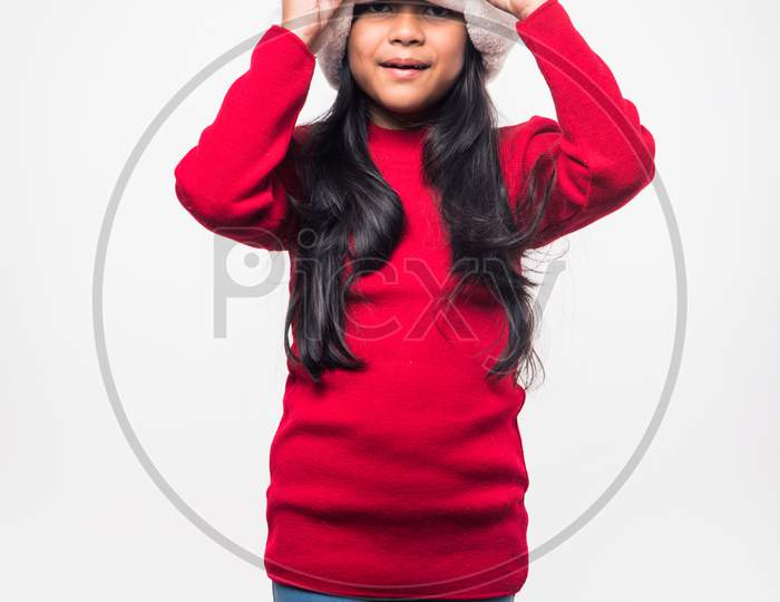 Cute little indian/asian girl celebrating Christmas while sitting in a Cardboard Box against red brick wall, indoor