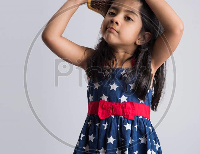 Indian cute girl combing hair with brush