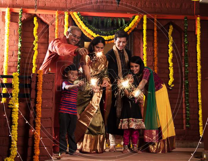 Indian Family celebrating Diwali festival with fire crackers