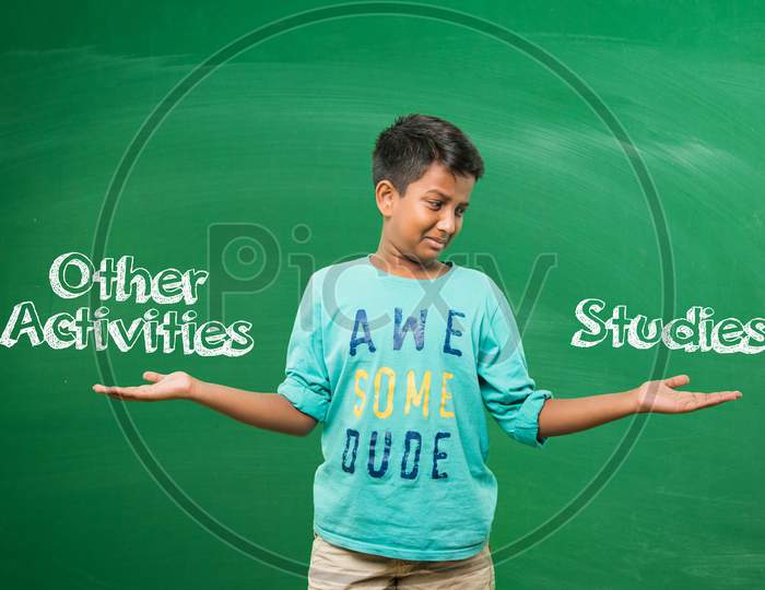 Little school boy standing in front of green scalk board with doodles - education and kids concept