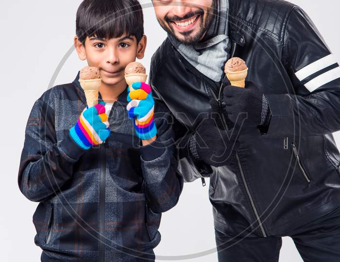 Indian Father and Son eating ice Cream in warm clothes on white background