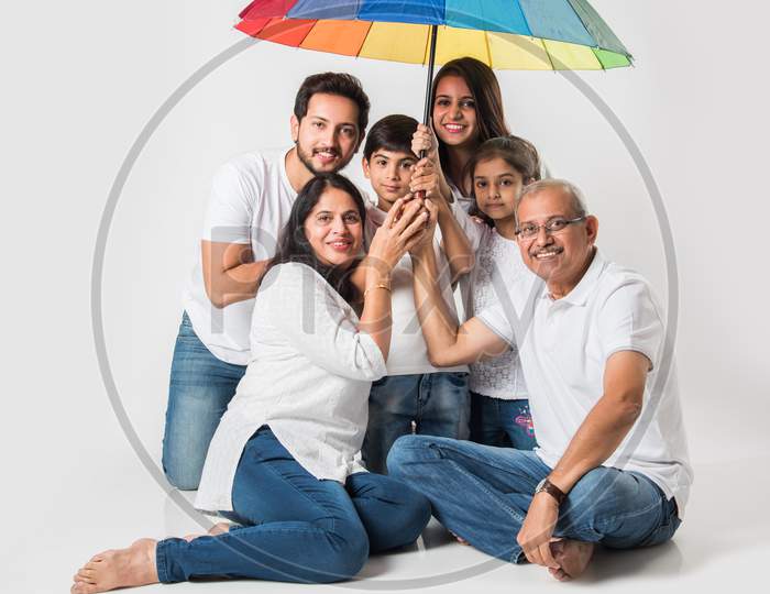 Indian Family sitting with Umbrella over white background. selective focus