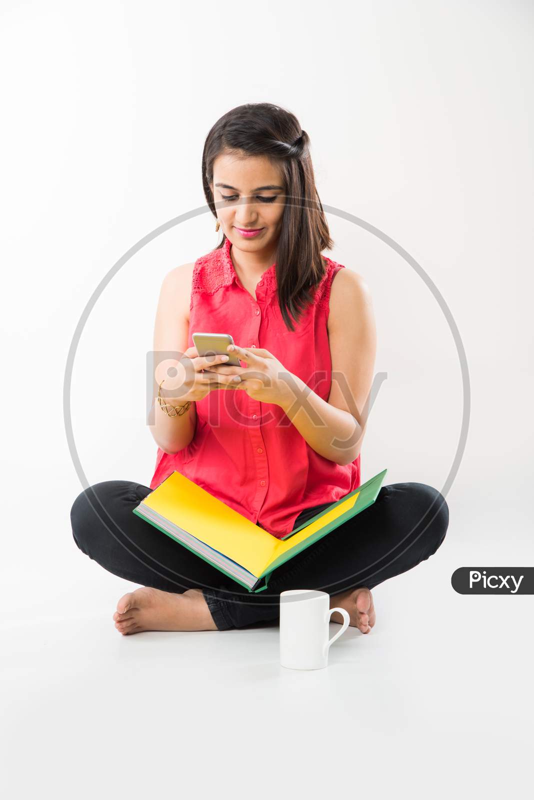Pretty Indian/Asian College Girl holding books and clicking selfie with smartphone, standing isolated over white background