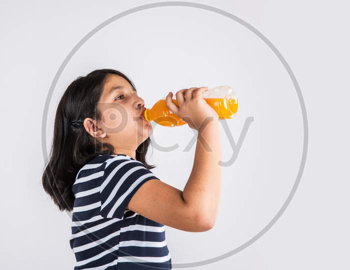 Cute little girl drinking mango juice or cold drink / beverage