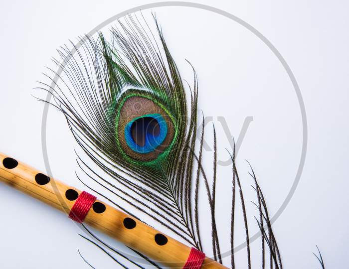 peacock feather and bamboo flute over colourful background