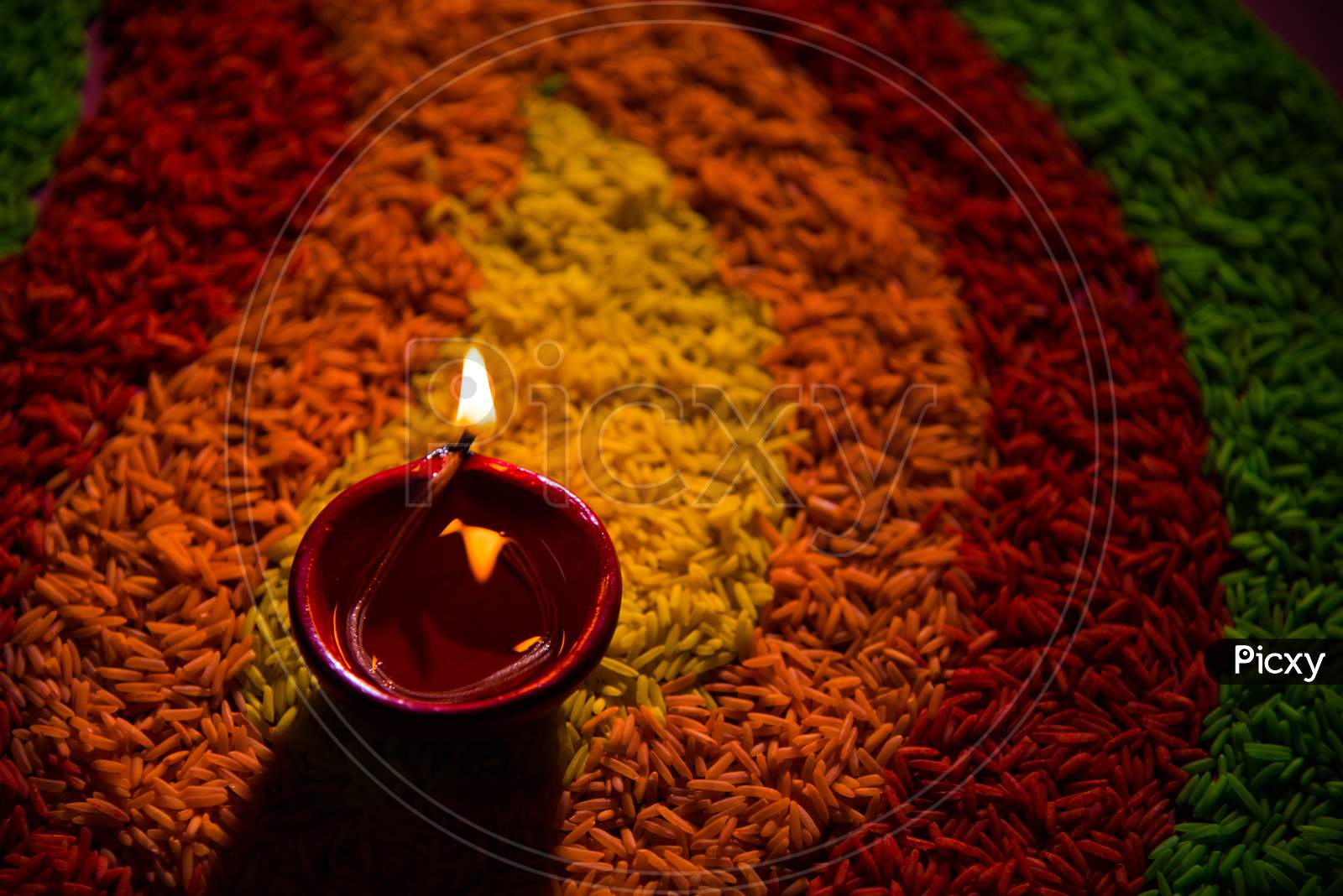 Diwali Diya over Rangoli made using Colourful Rice grains