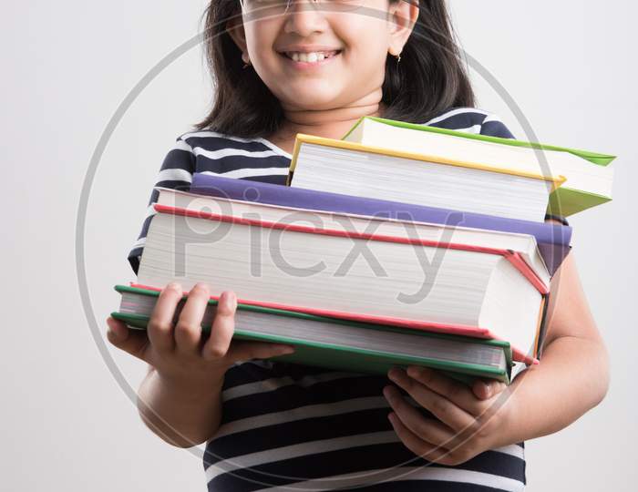 Indian school girl studying with book while standing
