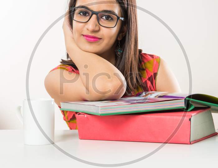 Pretty Indian/Asian collage Girl studying on tablet with pile of books