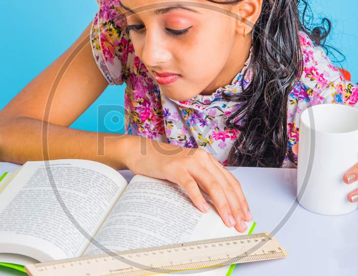 Indian school girl studying at home with books