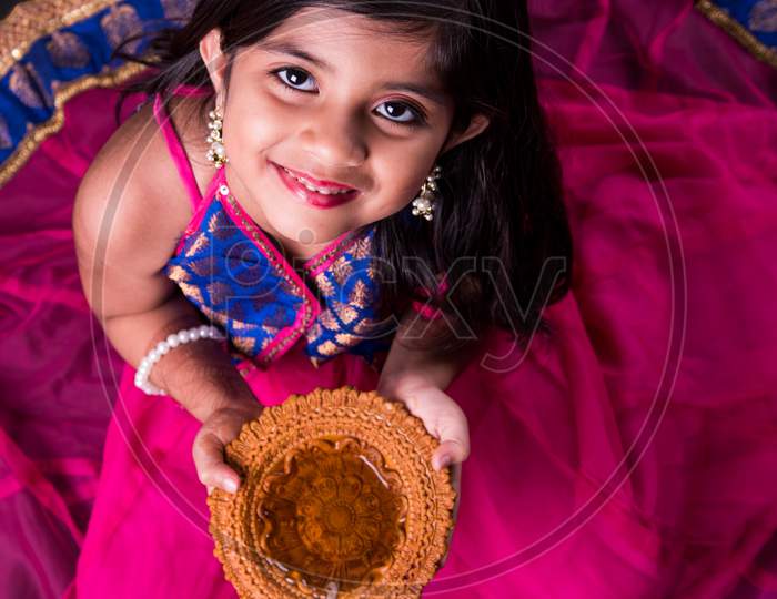 Narayanganj, Dhaka, Bangladesh. 4th Nov, 2021. A children poses for a  picture while taking earthen lamp or 'diya' on the occasion of Diwali, the  Hindu festival of lights in Narayanganj, Bangladesh. (Credit