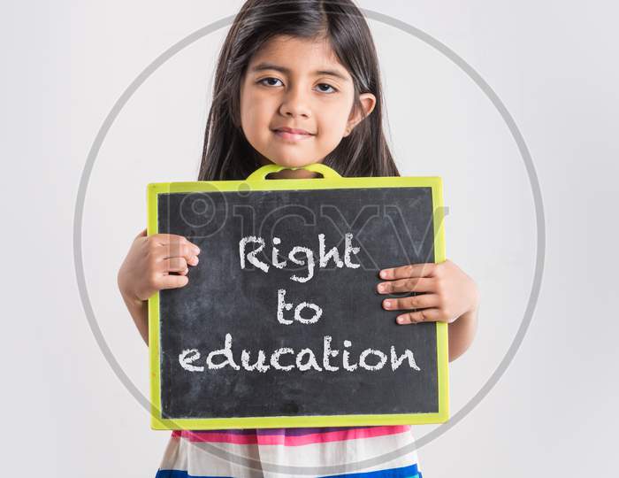 Cute little Indian girl holding and presenting blank school slate board, isolated over white background