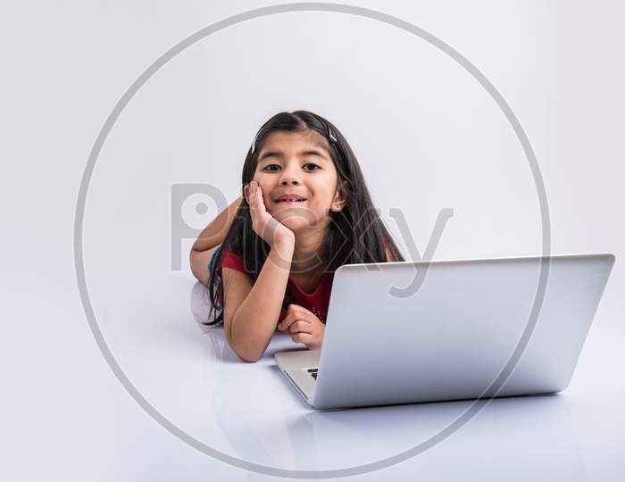 Indian school girl studying with laptop on floor