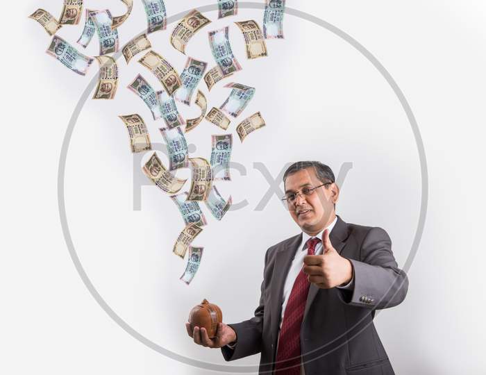 successful Indian handsome Businessman showing a piggy bank