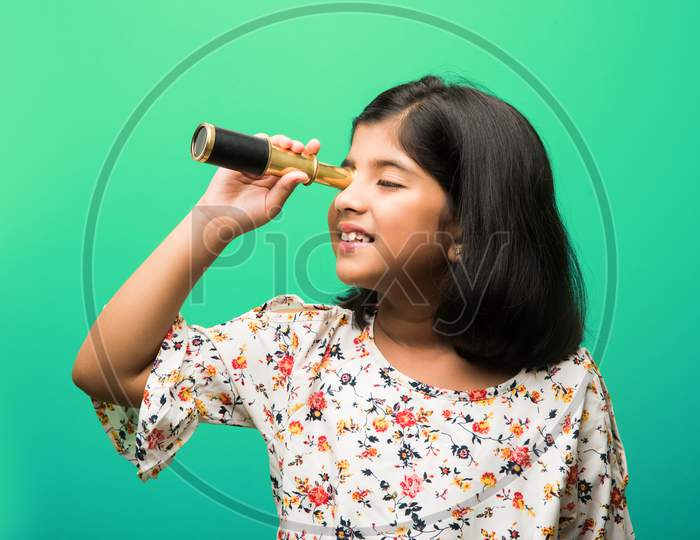 Cute little girl using stretch telescope and looking up in the sky
