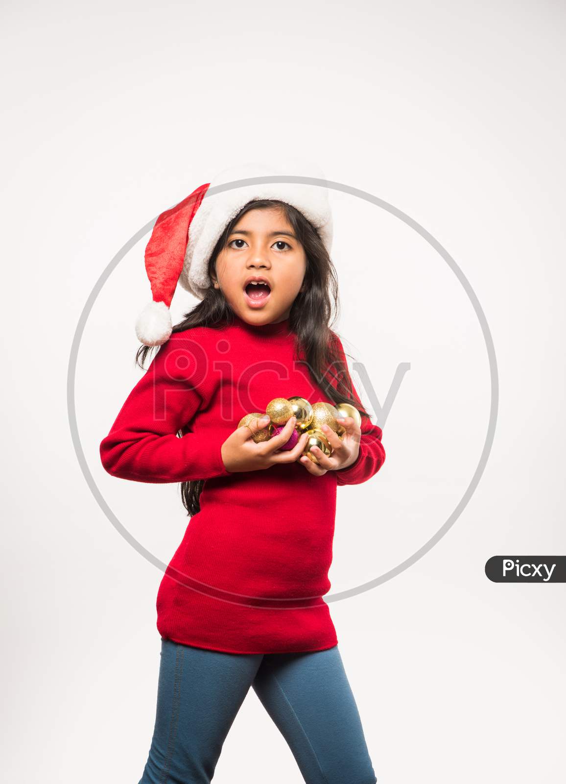 Cute little indian/asian girl celebrating Christmas while sitting in a Cardboard Box against red brick wall, indoor
