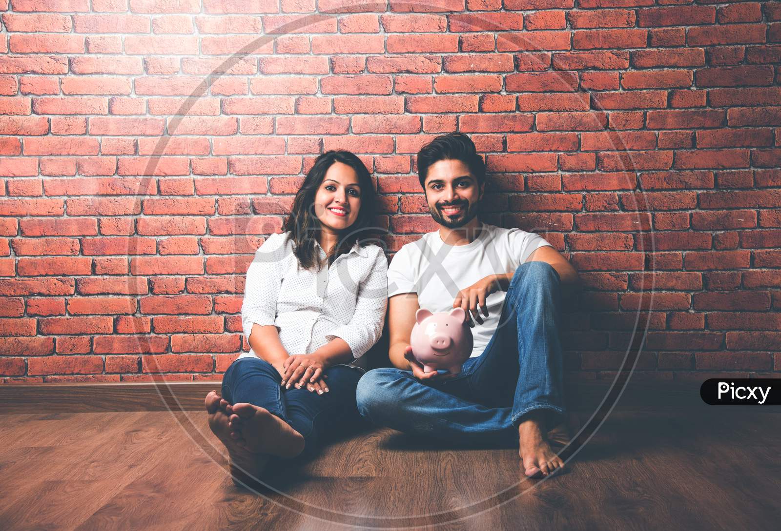 Indian couple with piggy bank, isolated over white background