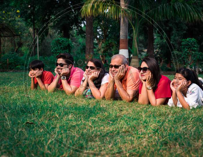 indian family lying on grass with hands on chin