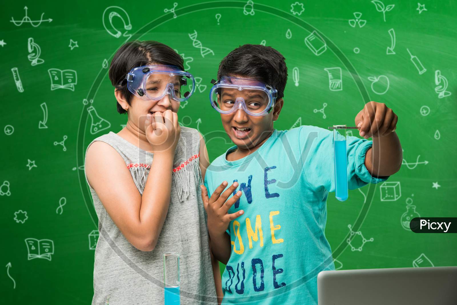 small boy and girl studying science in classroom against green chalkboard background with science doodles