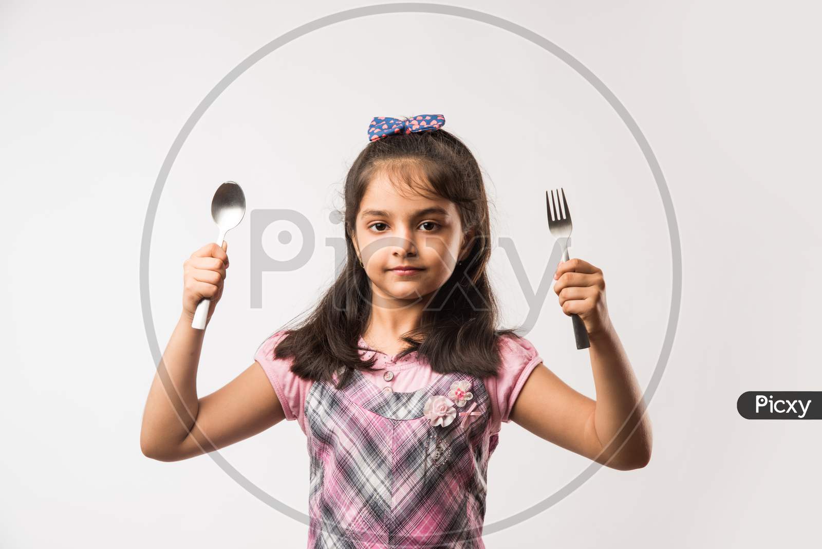 Small Girl showing spoon and fork over white background
