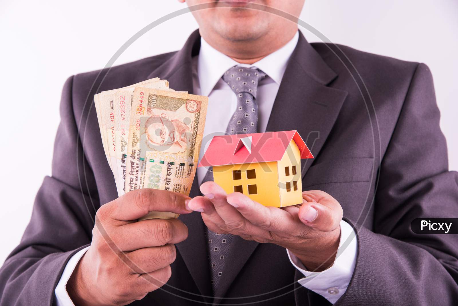 Home buying or real estate in India - Closeup of indian man holding indian Rupees and 3D home model
