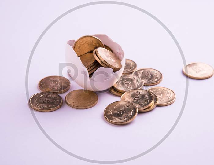 indian five rupee golden coins emerging from cracked egg, isolated over white background