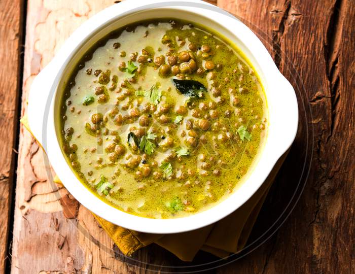 Black Masoor Dal fry or Dhaba Style Sabut Red Lentil dhal tadka in green curry, served in a bowl. selective focus