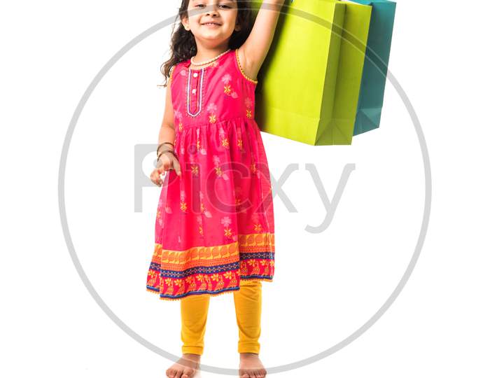 Indian small girl holding shopping bags, standing isolated over white background