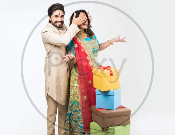 Indian Man giving surprise gift to wife, standing isolated over white background