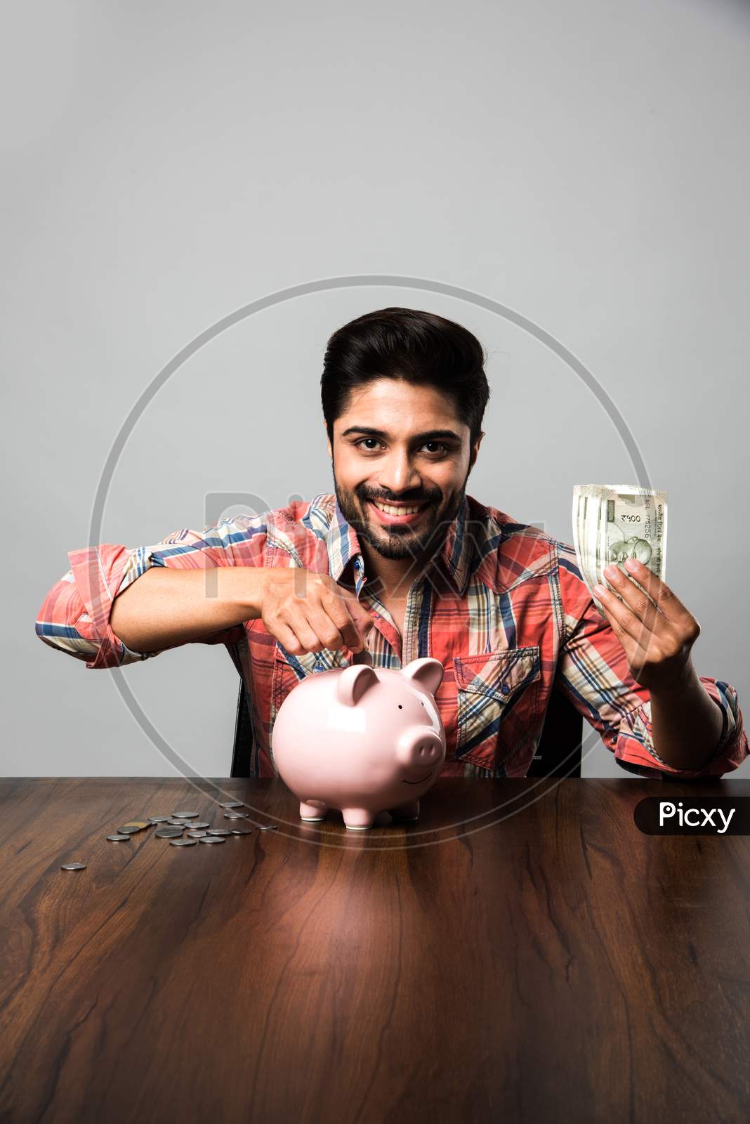 Indian Man with Piggy Bank, sitting at table