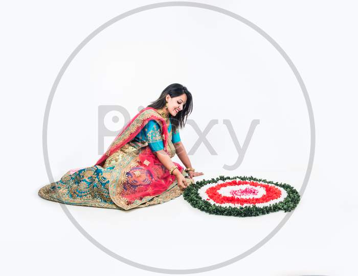 girl/woman making flower rangoli for hindu festival celebration, sitting over white background, selective focus