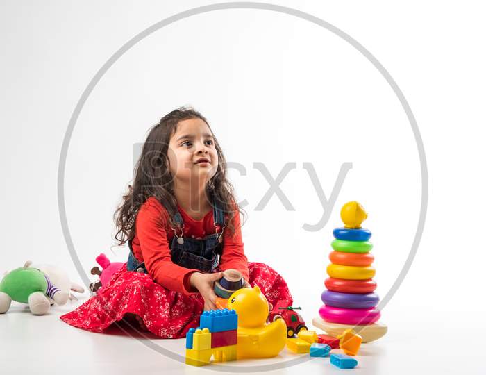 Indian Little child girl with stethoscope and Stuffed Baby or Puppy toy sitting against white background